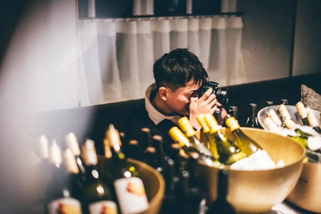 昏下拍攝葡萄酒瓶的人
